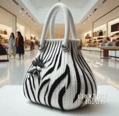 a zebra print purse sitting on top of a white table in a room filled with people