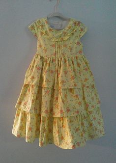 This garden summer frock is made by Laura Ashley. The yellow background with pink and coral flowers has 3 layers with cap sleeves. Underneath is a white cotton and tulle petticoat. It ties in the back. neckline button back  made of 100% cotton. needs to be pressed Frock Dress, Coral Flowers, Laura Ashley, Yellow Background, Petticoat, White Cotton, Summer Girls, Cap Sleeves, Girls Dresses