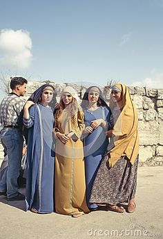 a group of people standing next to each other in front of a stone wall and blue sky