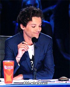 a man sitting at a table with a microphone in front of him and an orange cup next to him