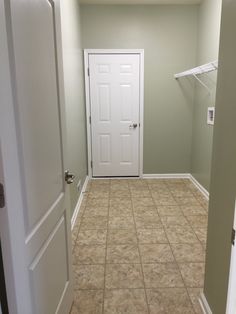 an empty room with tile flooring and white doors leading to another room in the background