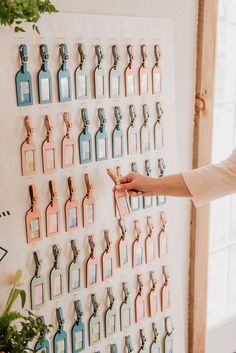 a woman pointing to a wall mounted with many different colored bottles and clips on it