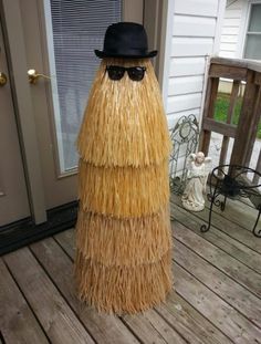 a man in a straw hat and sunglasses standing on a porch with a fake grass skirt