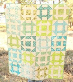 a person holding up a quilt in the grass