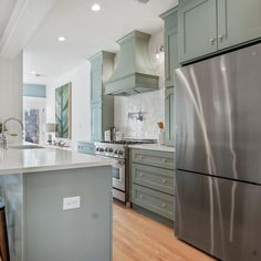 a kitchen with an island and stainless steel refrigerator freezer combo in the center, surrounded by blue cabinets