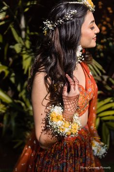 a woman with flowers in her hair is wearing a dress and holding a flower crown