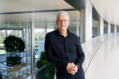 an older man standing in front of a glass wall with his hands clasped to his chest