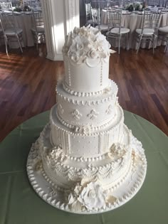 a large white wedding cake sitting on top of a green table cloth covered tablecloth