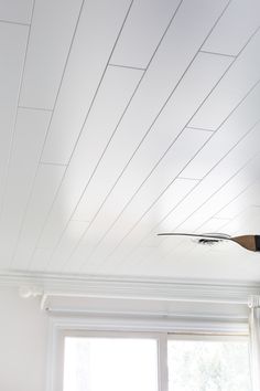 a ceiling fan is hanging from the ceiling in a room with white walls and windows