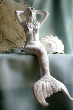 a white mermaid statue sitting on top of a table