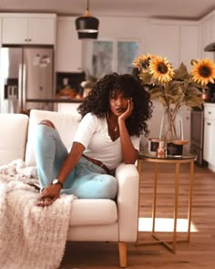 a woman sitting on a couch talking on a cell phone with sunflowers in the background