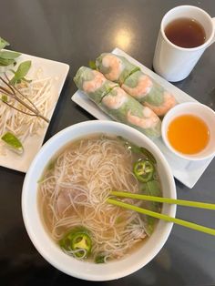 a table topped with plates of food and bowls of soup next to chopsticks