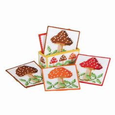 four cross stitch coasters with mushrooms on them