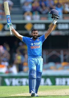 a cricket player holding his bat up in the air with both hands and wearing a helmet