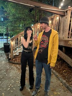 a man and woman standing next to each other in front of a wooden deck area