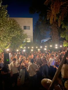 a large group of people standing around each other in front of a building at night