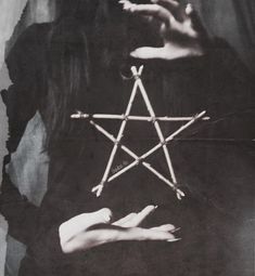 a black and white photo of a woman holding an inverted pentagramil in her hands