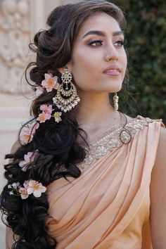 a woman in an orange dress with flowers in her hair and earrings on her head