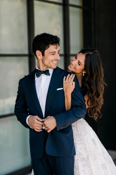 a man in a tuxedo and a woman in a wedding dress smile at each other