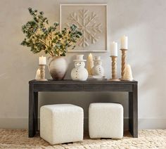 a wooden table topped with two white stools next to a vase filled with flowers