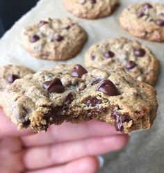 a person holding up a chocolate chip cookie