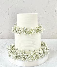 a white wedding cake decorated with baby's breath flowers is on the instagram page