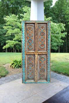 an old wooden door sitting in the middle of a yard with grass and trees behind it