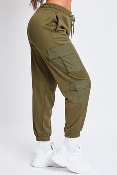 Keep it cute and casual in our Women’s Joggers with Nylon Pockets. These trendy mixed-media joggers are constructed with a soft, midweight polyester fabric and feature pleated flap cargo pockets made of parachute-style material. These lounge pants feature an elastic waist with drawstring closure, inseam front pockets, and an elastic hem. Style with a fitted tank and sneakers for an on-trend sporty vibe. Product Details- High-Rise- Elastic Waist with Drawstring Closure- Inseam Front Pockets- Doub Green Athleisure Parachute Pants With Pockets, Green Joggers With Pockets For Fall, Khaki Sweatpants With Pockets For Loungewear, Green Nylon Cargo Pants, Athleisure Style, Sporty Bottoms With Pockets And Cuffed Ankles, Khaki Joggers With Cargo Pockets For Streetwear, Stretch Khaki Cargo Parachute Pants, Sporty Khaki Joggers With Pockets, Utility Sweatpants With Multiple Pockets For Loungewear