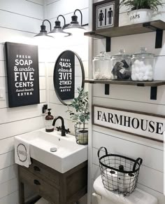 a white bathroom with black and white signs on the wall, toilet and sink in it