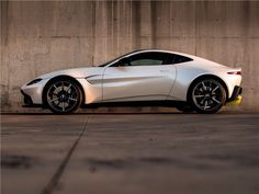 a white sports car parked in front of a concrete wall