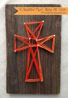 an orange string art piece on top of a wooden board with the words, beautiful mess strong at cross