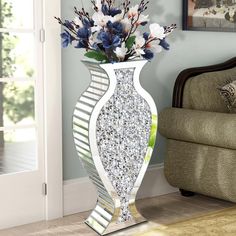 a vase filled with flowers sitting on top of a wooden floor next to a couch