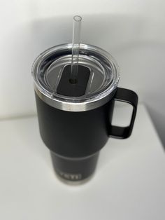 a black cup with a straw in it sitting on a table