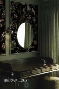 a desk with a mirror on it next to a window covered in floral wallpaper