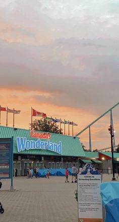 the entrance to canada's wonderland is lit up at dusk with pink clouds in the sky