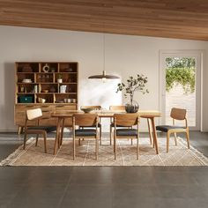 a dining room table and chairs in front of a bookshelf with open doors