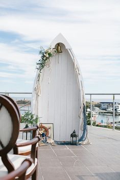 an outdoor ceremony setup with chairs and flowers on the back wall, next to a white boat