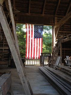 an american flag hanging from the side of a wooden building with benches and ladders