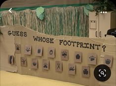 a cardboard board with handprints on it and grass growing over the top that says guess who's footprints?