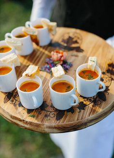 several cups of soup on a wooden tray