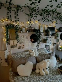 a bed with stuffed animals on it in a room filled with plants and pictures hanging from the ceiling