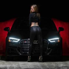 a woman standing next to a black car