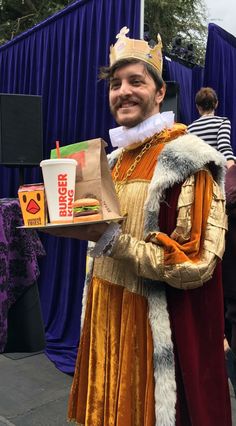 a man dressed up as a king holding a sandwich