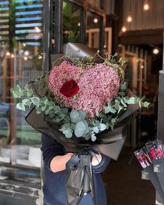 a woman holding a bouquet of flowers in front of a store