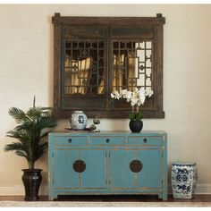 a blue cabinet with flowers and vases on top