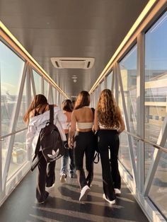 several people are walking down a walkway in an airport