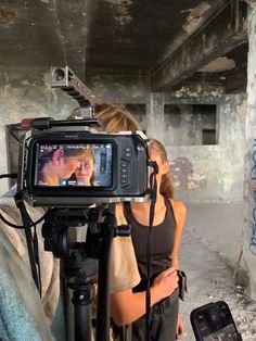 a man and woman standing next to each other in front of a camera on a tripod