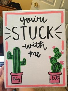 someone holding up a card that says you're stuck with me and two cacti