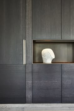 a white vase sitting in the middle of a wooden cabinet next to a wall mounted shelf