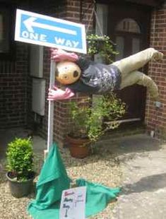 a stuffed animal hanging from a pole next to a one way sign and potted plants